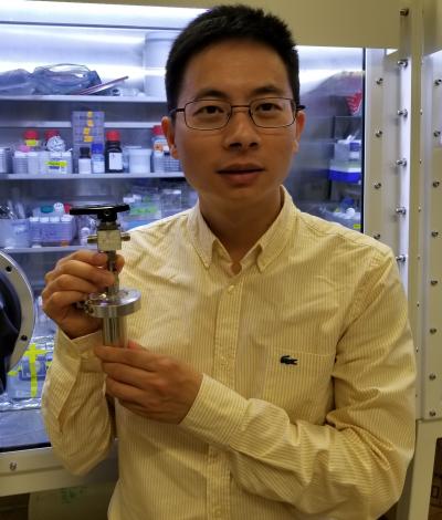 Postdoctoral scholar Wei Chen holds a prototype of Stanford’s water-based battery.